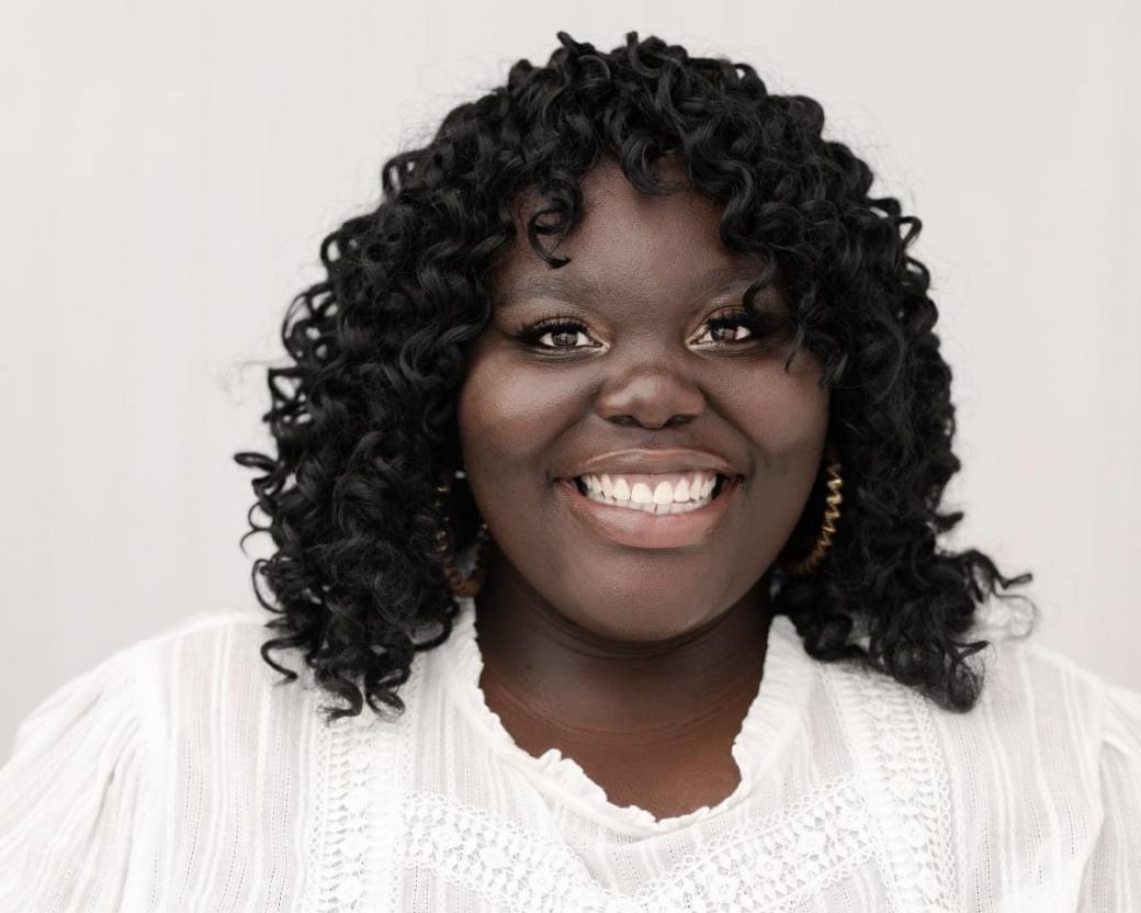 Sarah Adomako-Ansah wearing a white shirt in front of a white background is smiling.