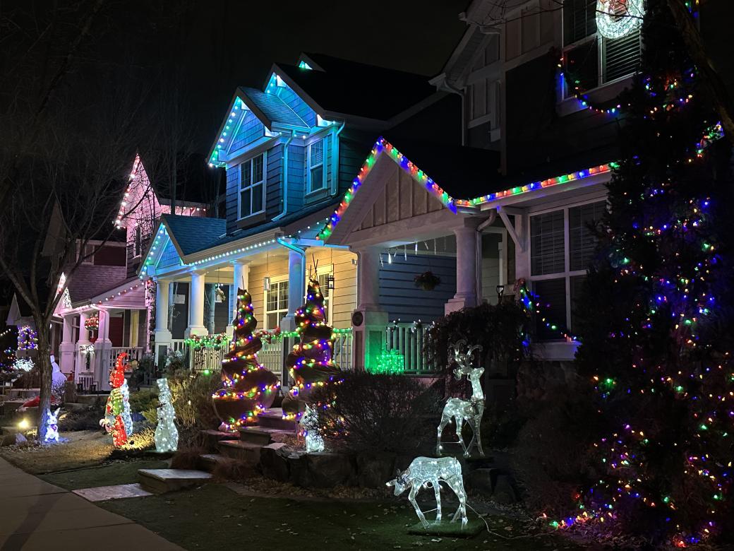 Three homes decorated with lights and Christmas ornaments standing on the lawns.