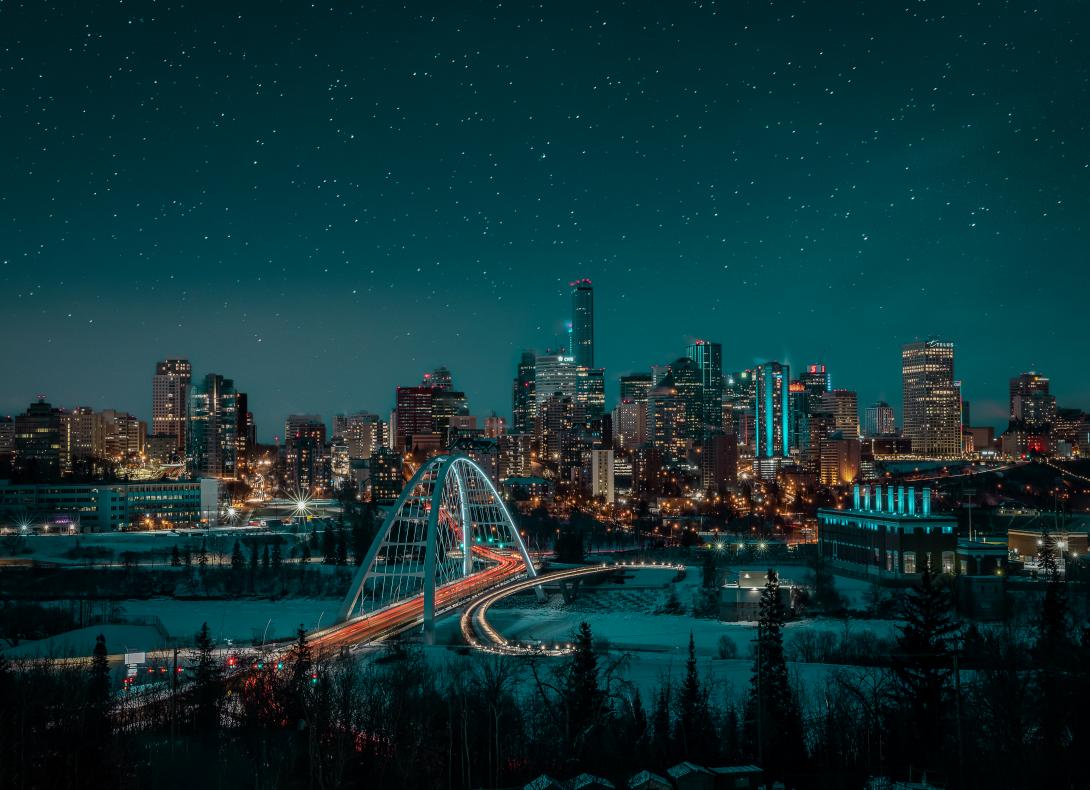 A view of a bridge, Edmonton’s downtown skyline, and stars in the night sky.