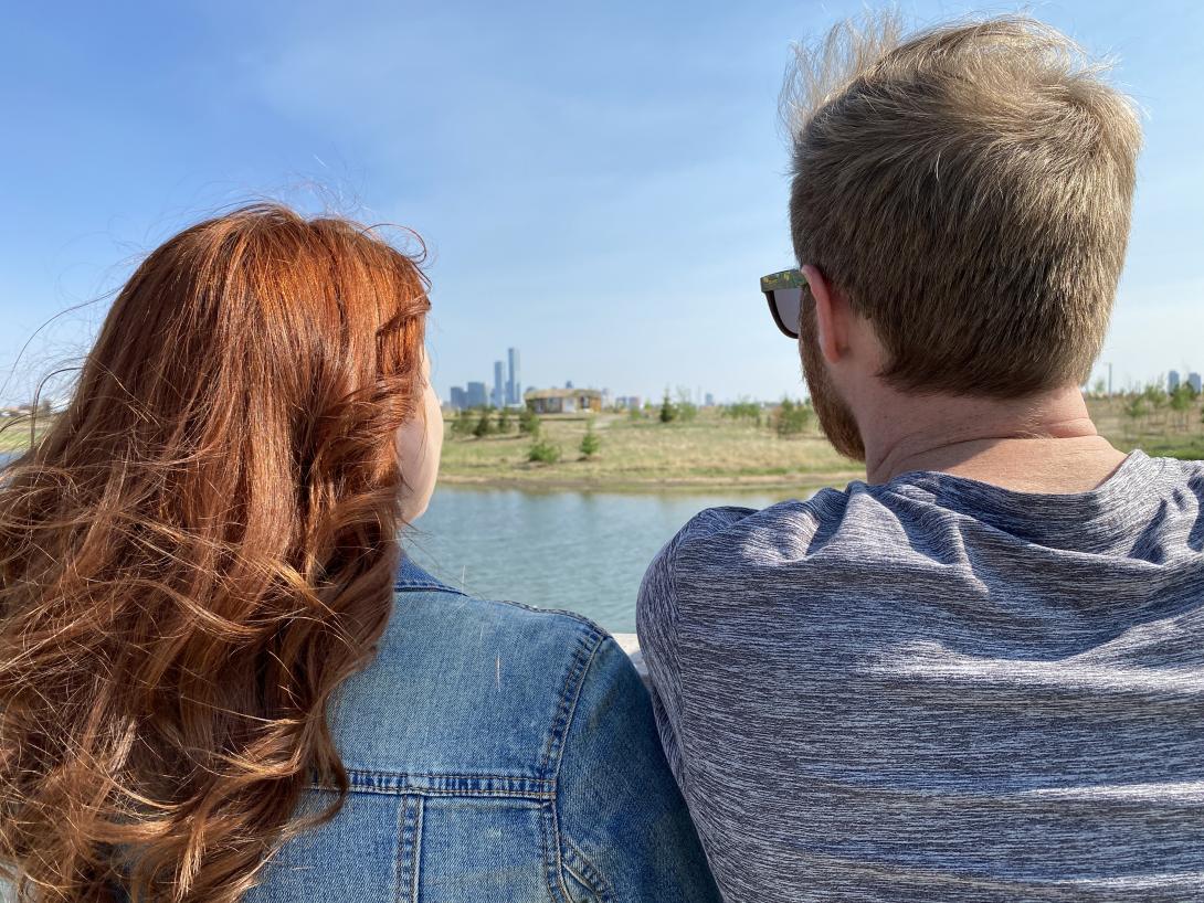 The backs of a couple looking towards a downtown skyline