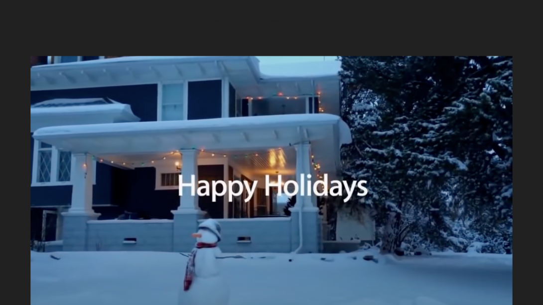 Screenshot of the exterior of a heritage home with a wrap around porch in winter. A snowman sits on the front yard. 