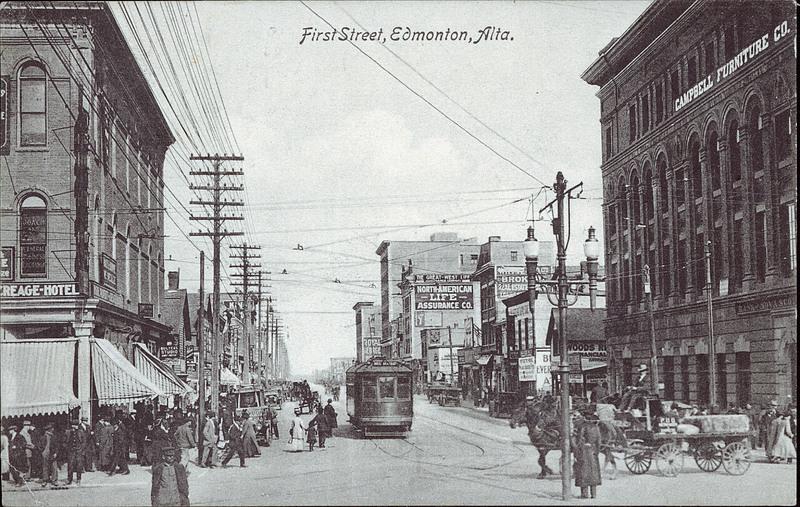A commercial street in Edmonton with stores, sidewalks and pedestrians on both sides. A streetcar runs down the middle of the street.