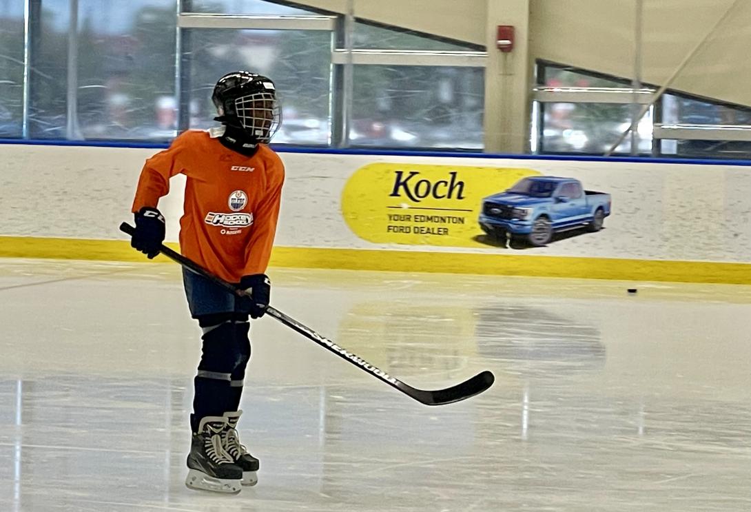 A young hockey player skates on the ice with a hockey stick in her hands.