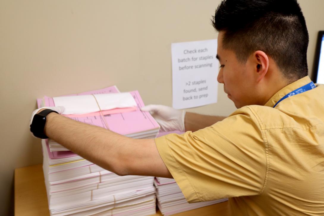 A young man stacking groups of papers working in an office. 