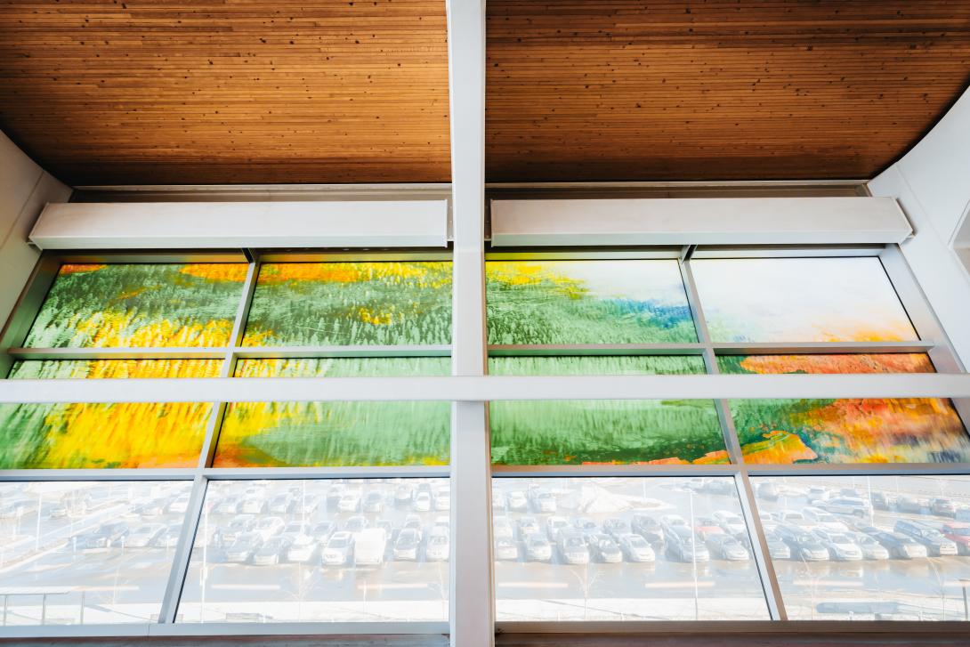 Glass artwork of diverse landscapes of green grass and yellow canola.
