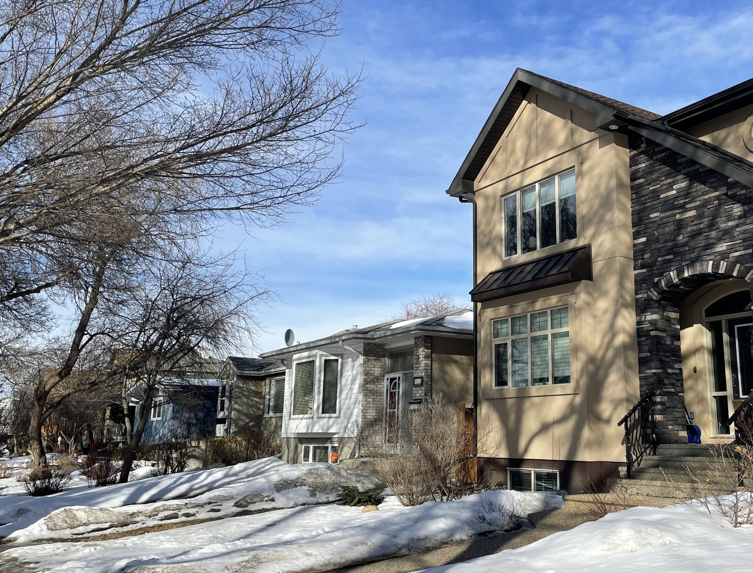 A newer home next to an older home on a neighbourhood street.