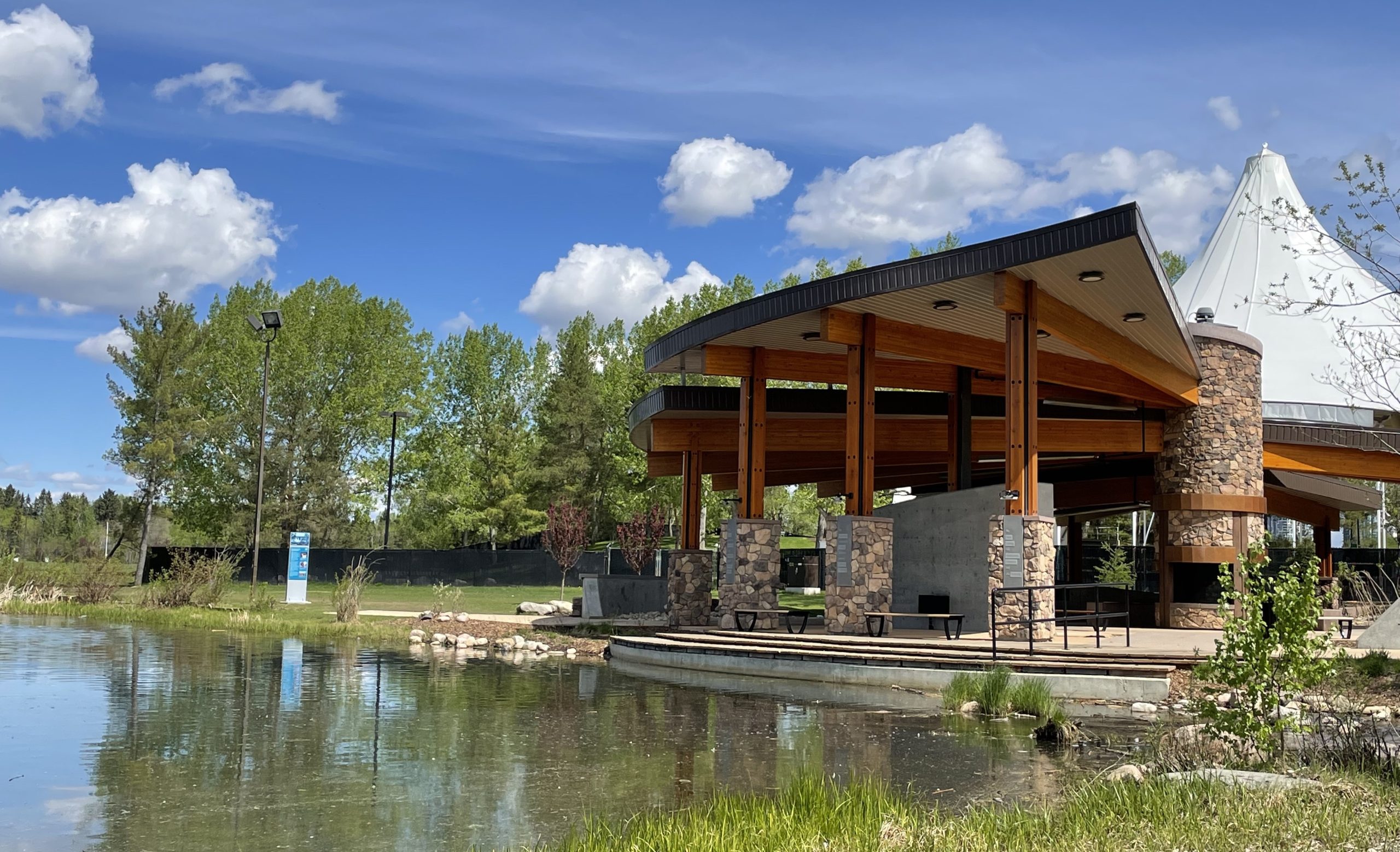 A veranda with stone pillars sits next to a lake.