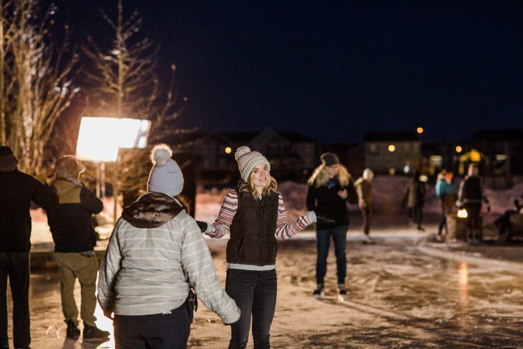 An actress and crew on set of an outdoor skating rink while filming a Christmas movie.