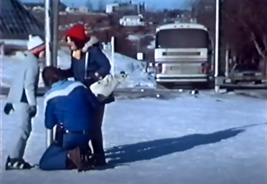 Screenshot from a movie where parents are trying to helpe a kid with his tongue stuck to a pole in winter.