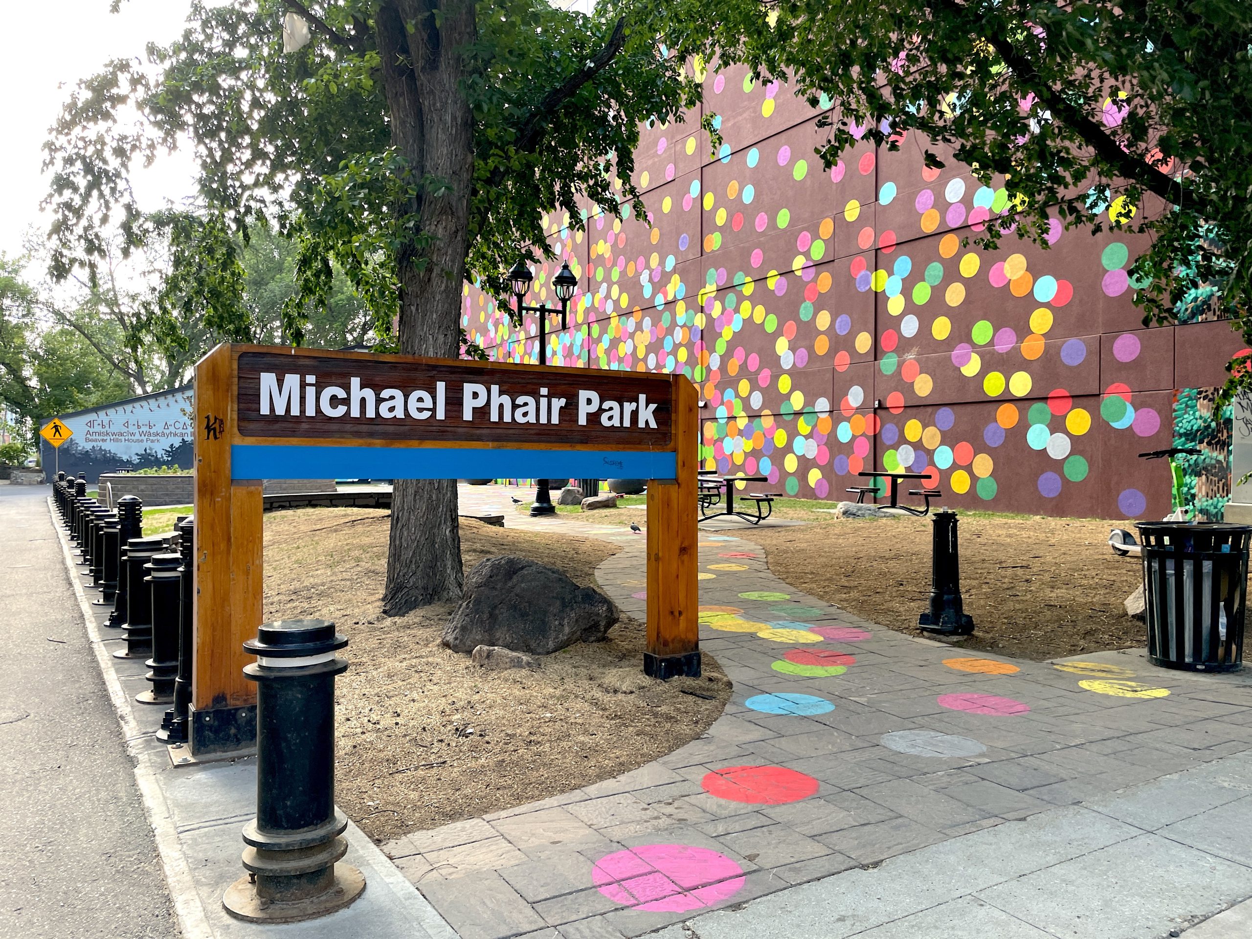 The park sign reads 'Michael Phair Park' and the park features colourful polka-dot pathways and wall.