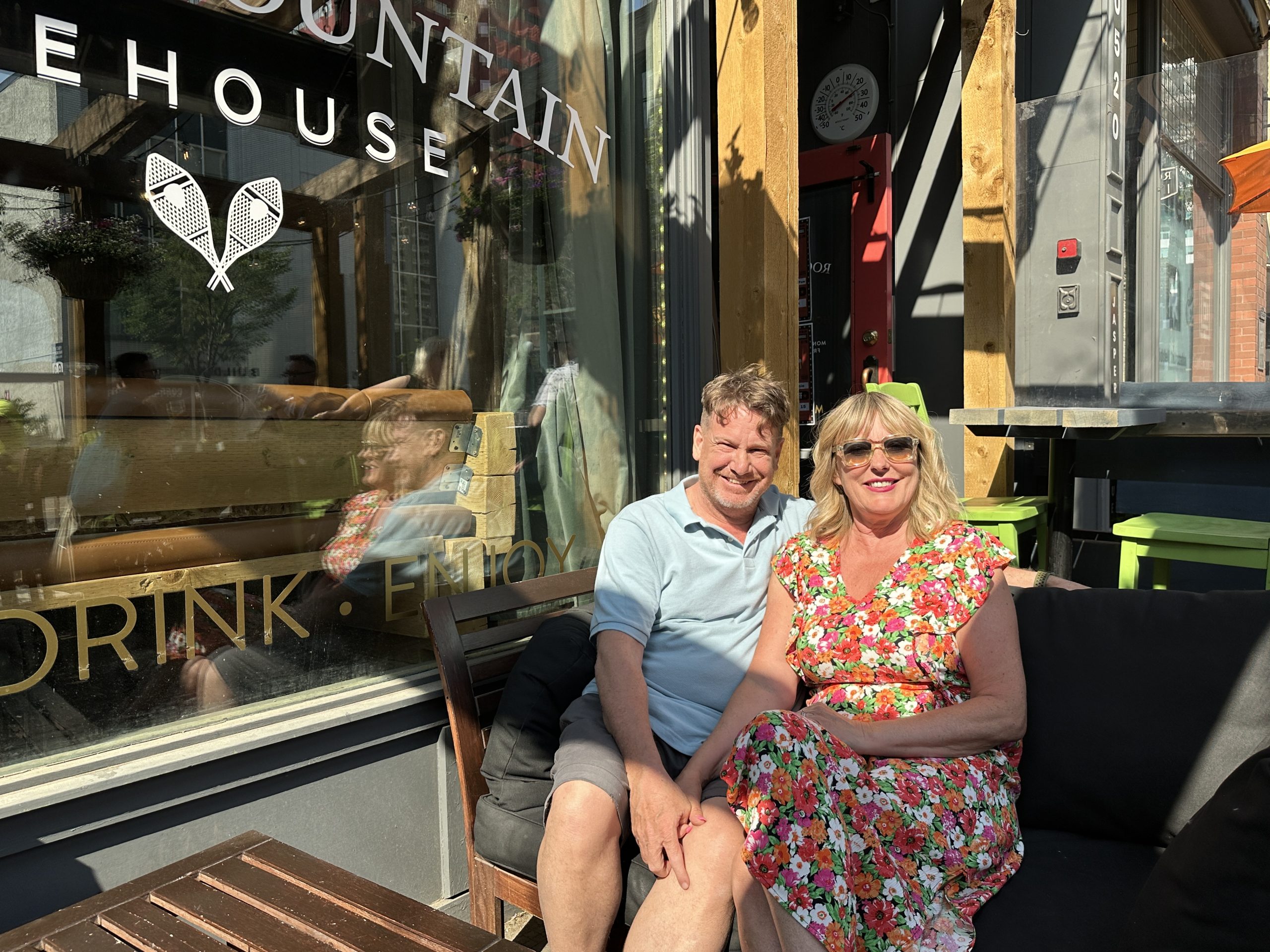 A man and a woman sit on a couch on a sidewalk patio outside a bar/restaurant. Credit: Owned by the City.