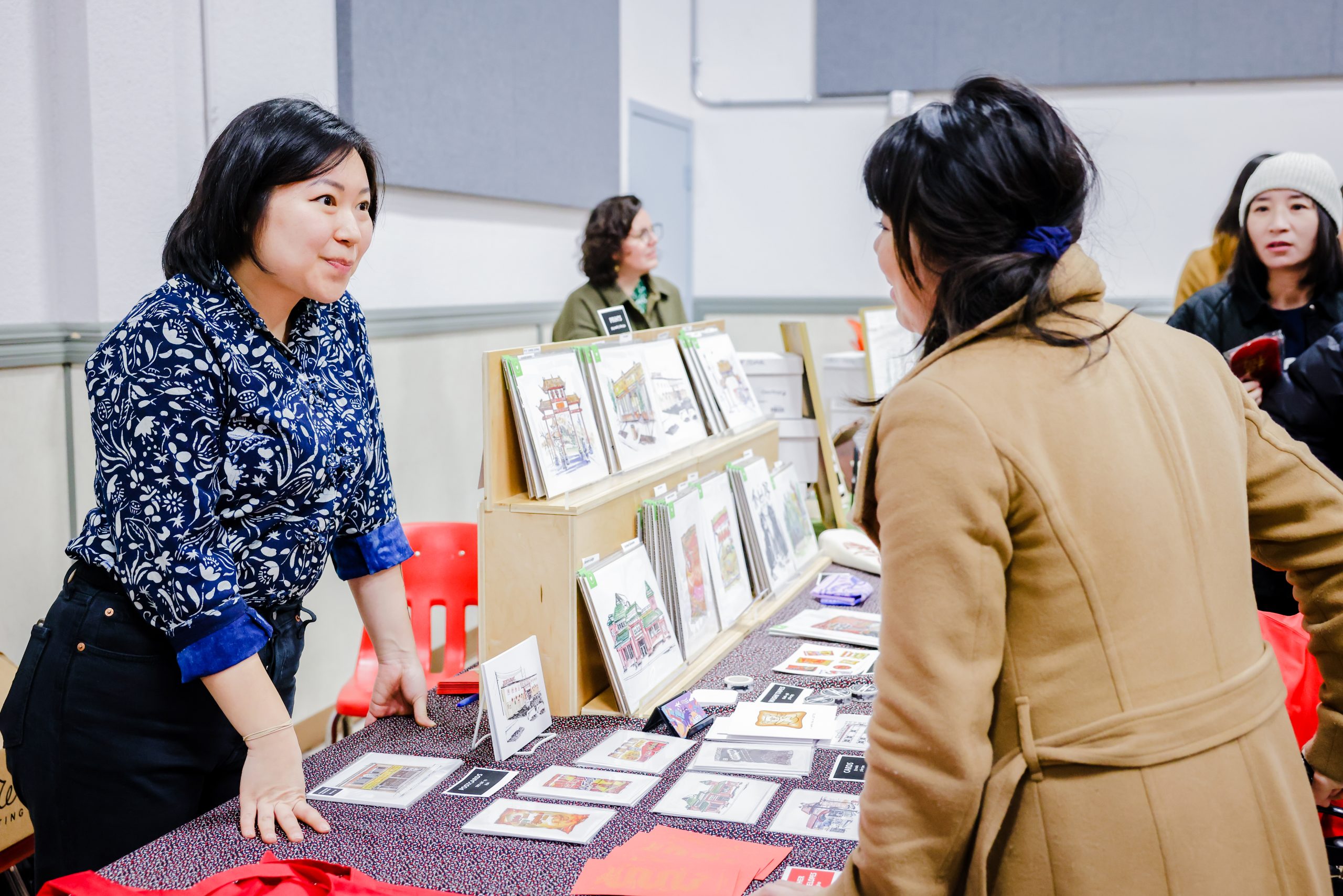 A customer approaching Emily Chu's kiosk featuring her prints of her artwork