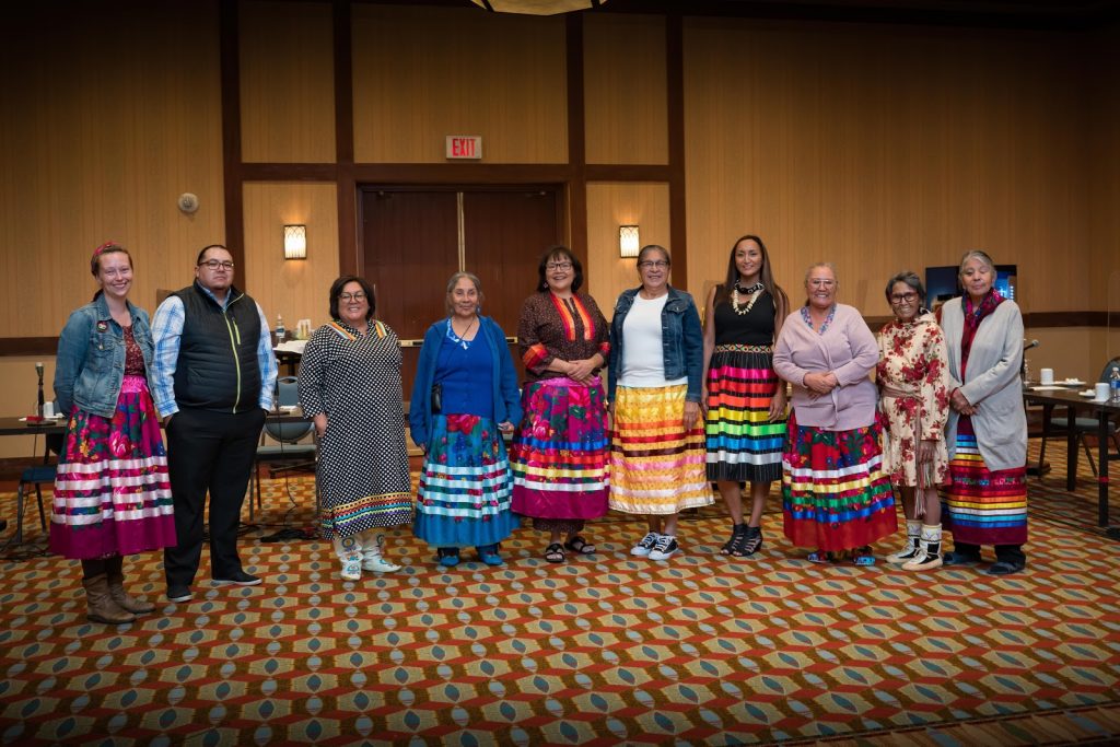 Ten indigenous leaders, mostly women in colourful skirts, stand in a meeting room.