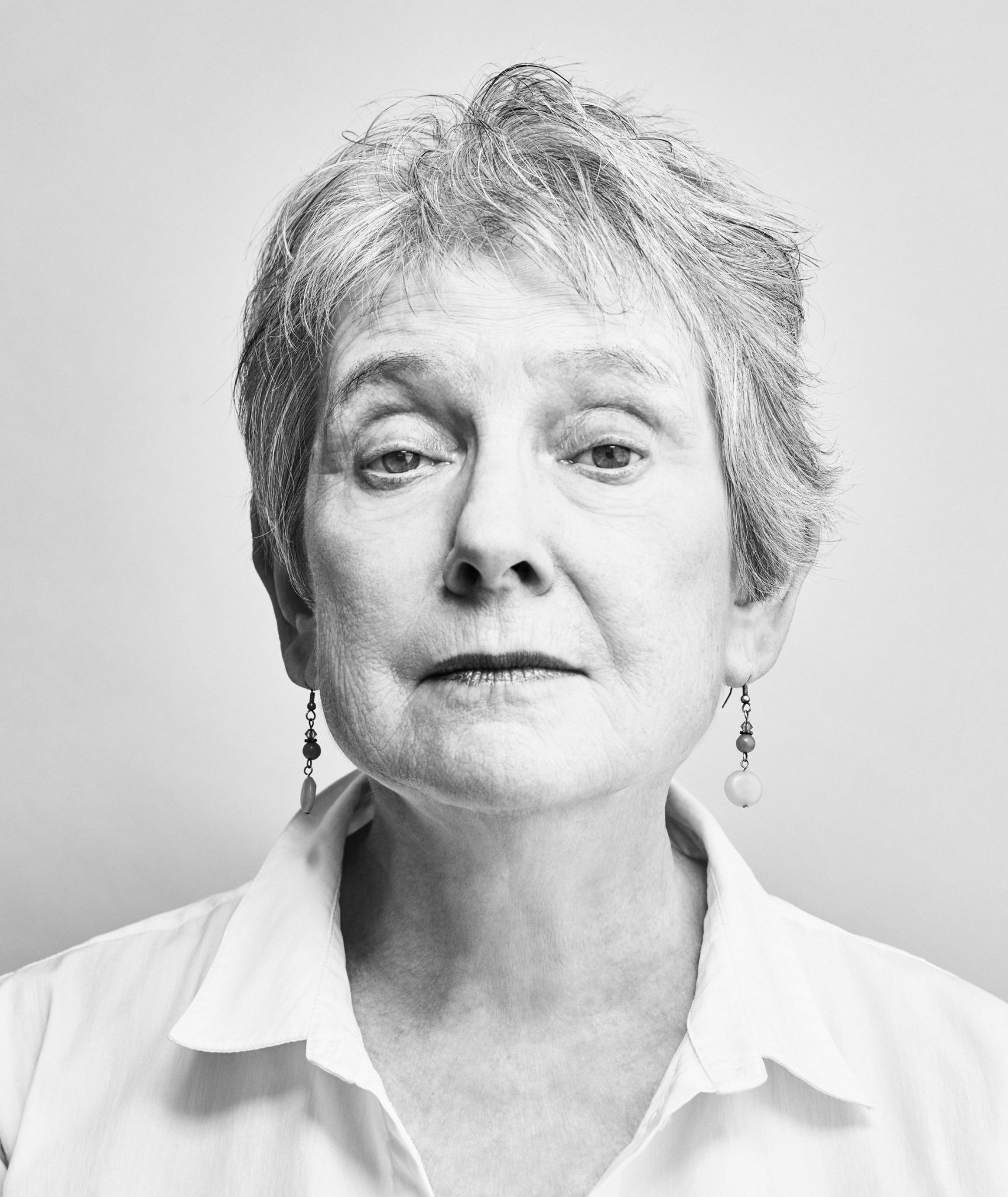 a woman with short hair and a white blouse poses for a black and white portrait.