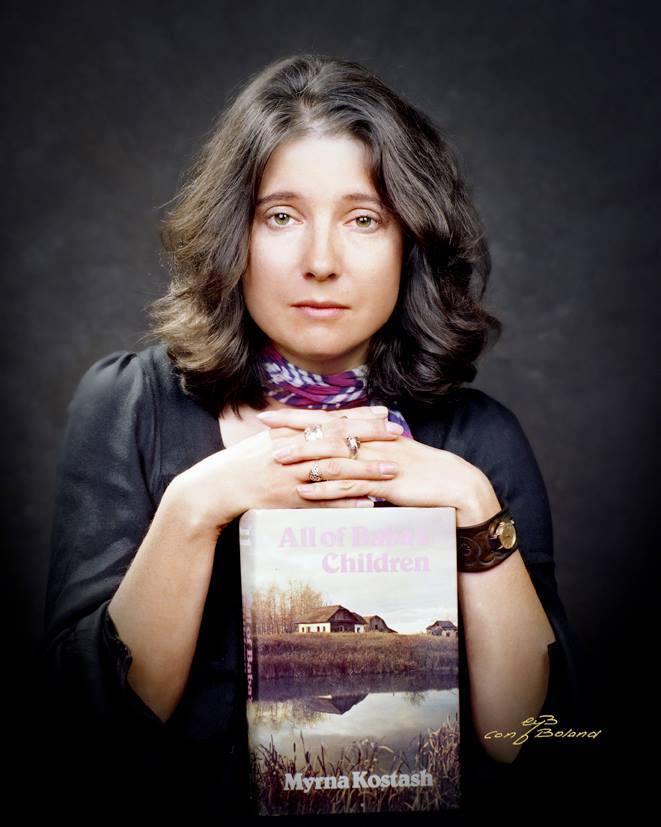 A woman poses for a portrait with her book, All of Baba’s Children, resting under her hands.