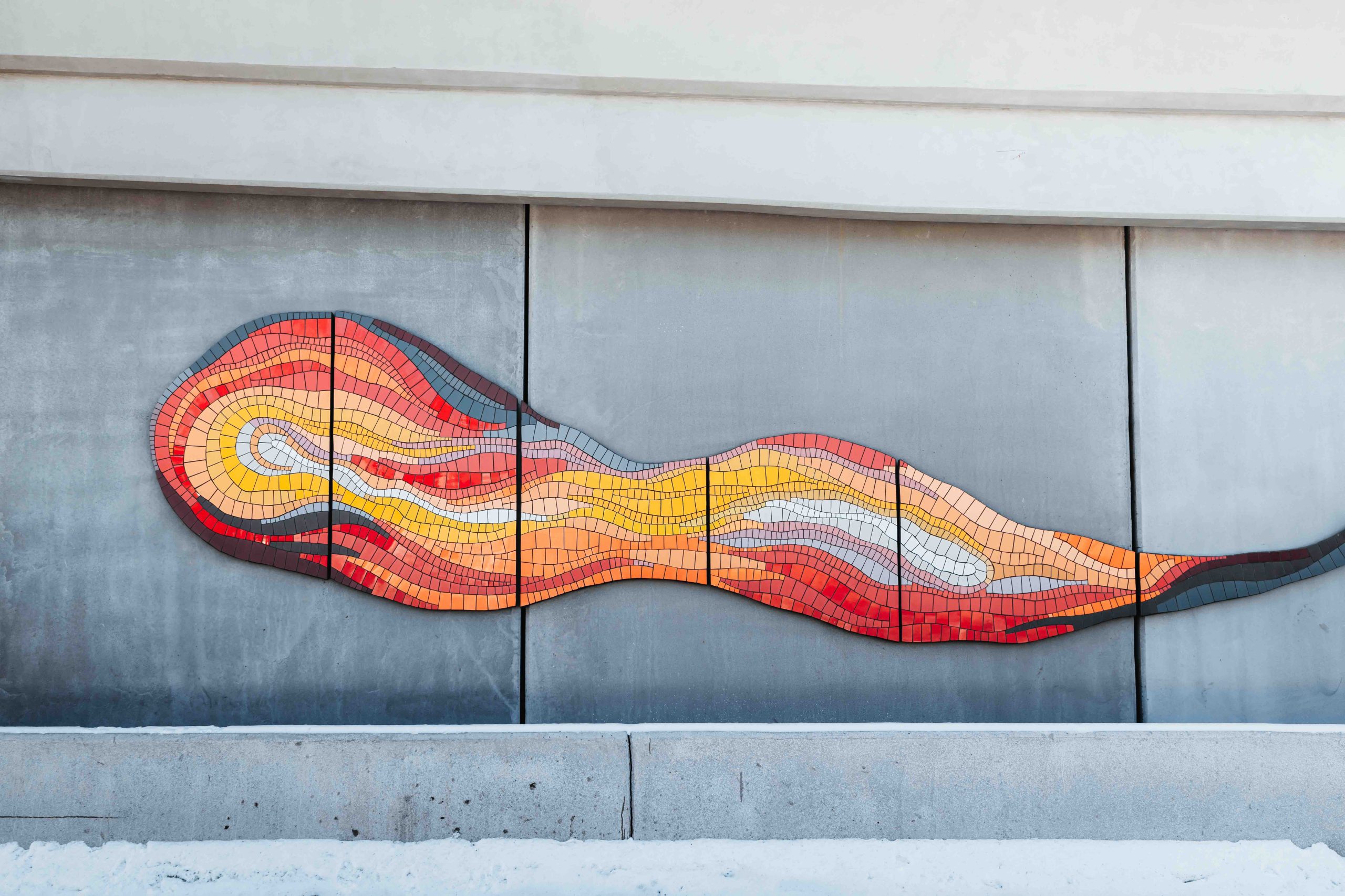 Mosaic tiles arranged in the pattern of a two-tailed comet add colour to a concrete ramp.