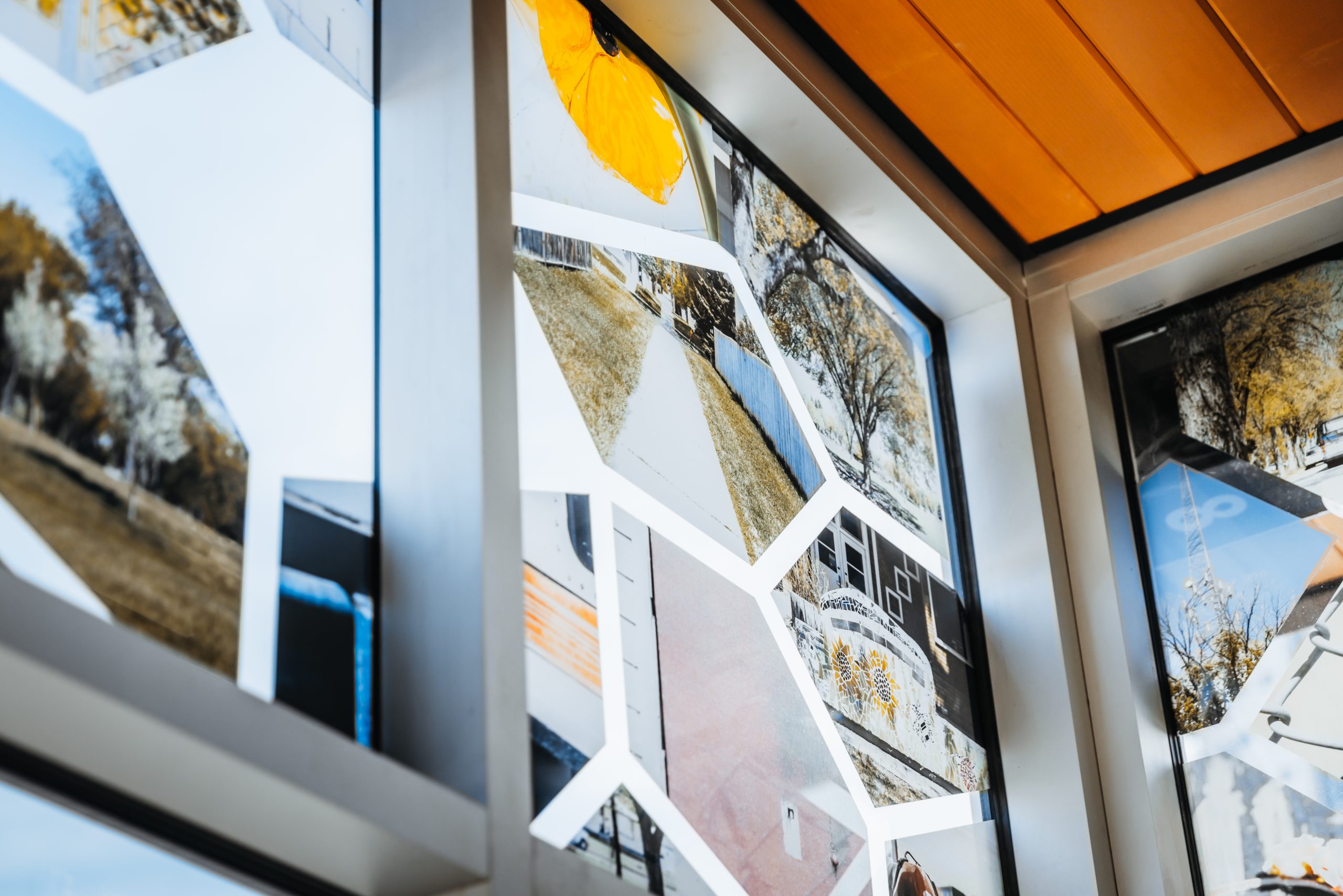 Windows of an LRT shelter are decorated with photographs of trees, sidewalks, and tile art.