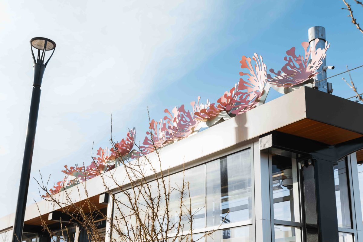 The top of an LRT shelter is decorated with sculptures of pink flowers that look like satellite dishes pointing to the sky.