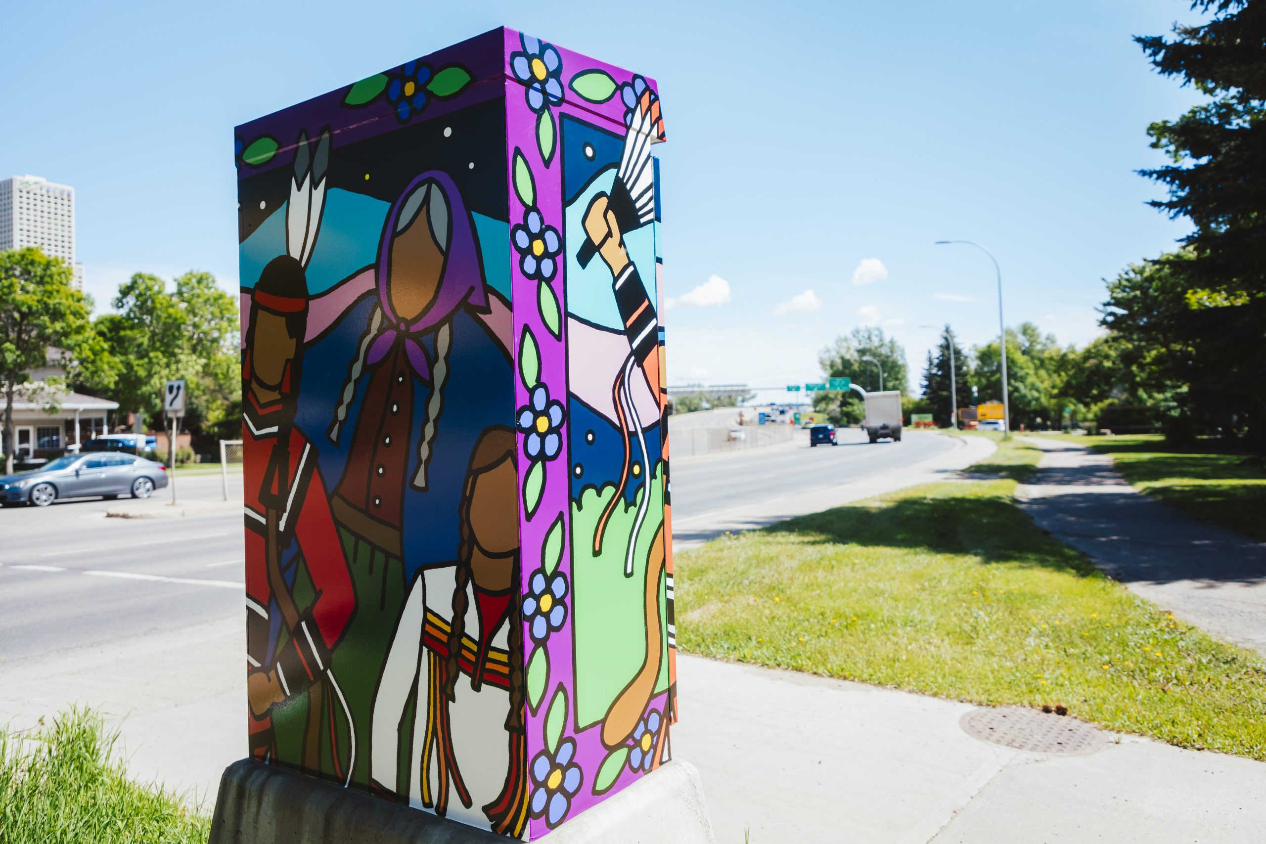 A traffic control box wrapped with art of an Inuit elder, a Métis boy and a First Nations dancer.