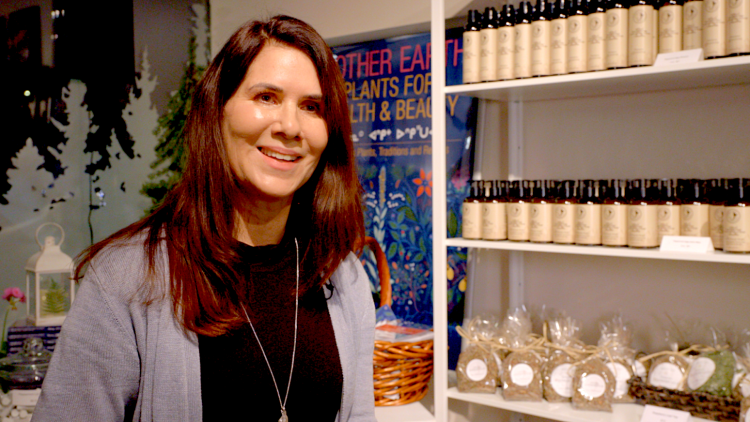 Carrie Armstrong standing in front of a shelf of bottles inside her store.