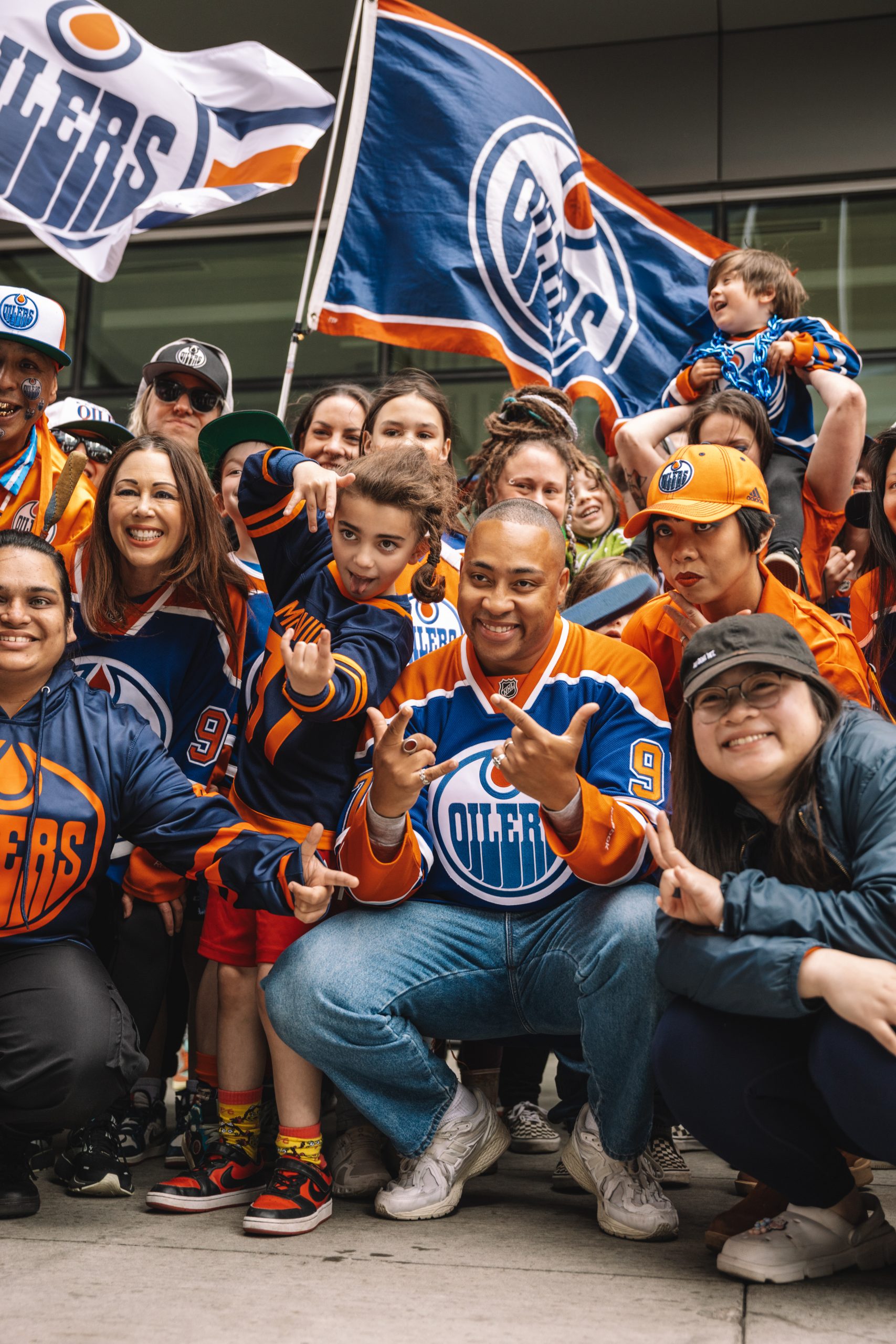 Cadence Weapon wearing an Oilers jersey surrounded by a group of people wearing Oilers jerseys.