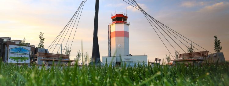 Entrance feature designed to resemble struts of a biplane between two benches with Blatchford Control Tower in the background.