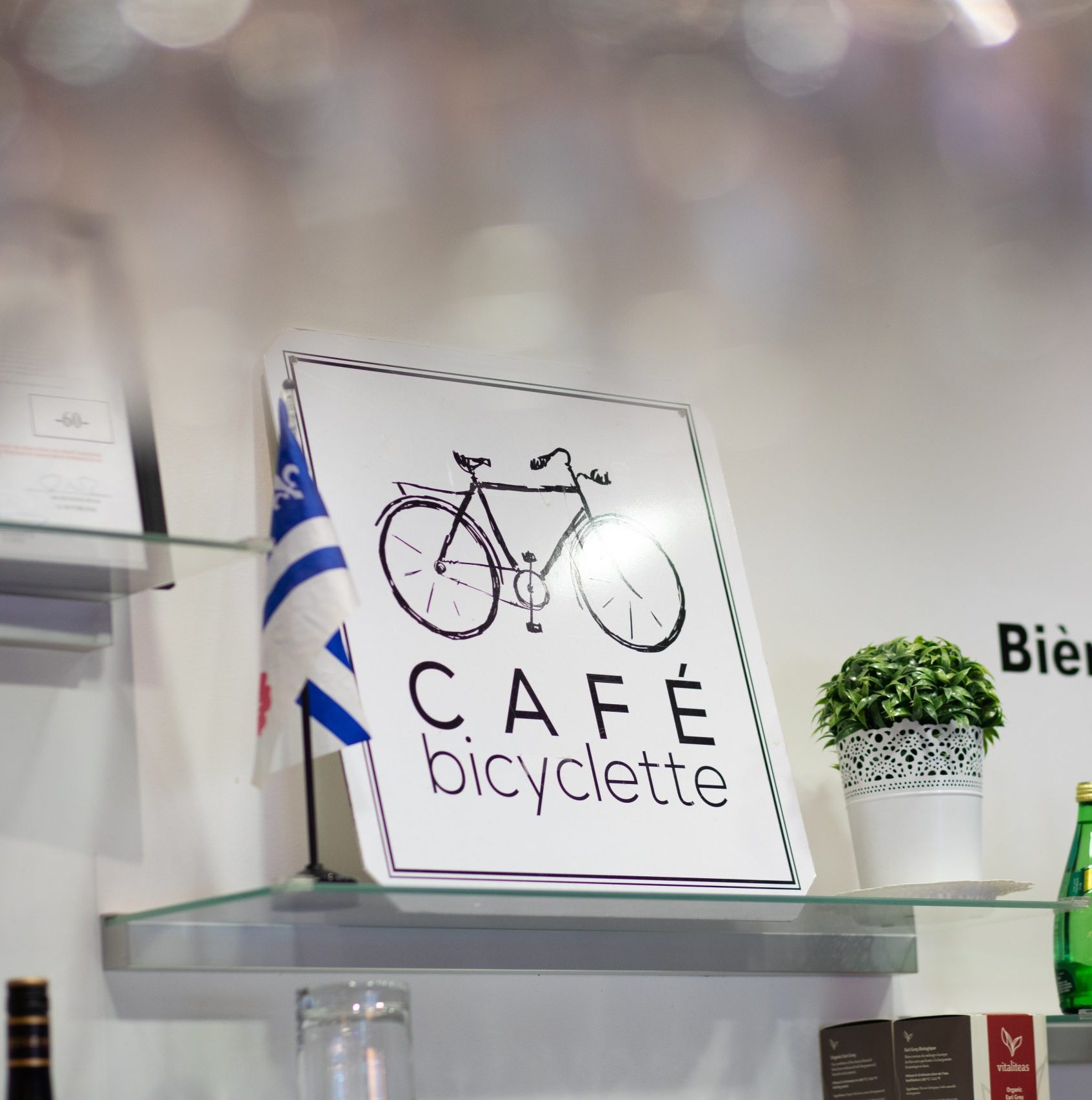 Cafe Bicyclette sign behind counter with framing from decorations on the top of the image.