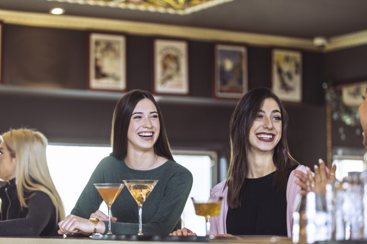 Two customers sitting at the bar, laughing and enjoying drinks at local French restaurant Le Petite Iza