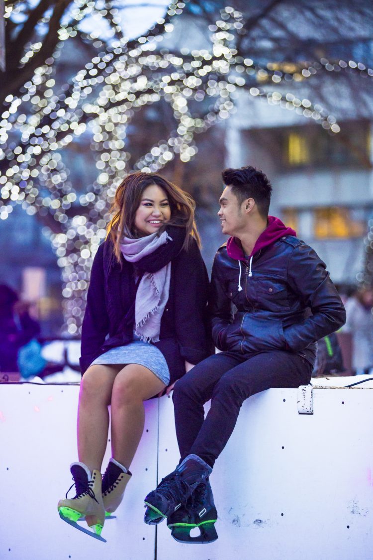 Two people sitting on a side board with skates on