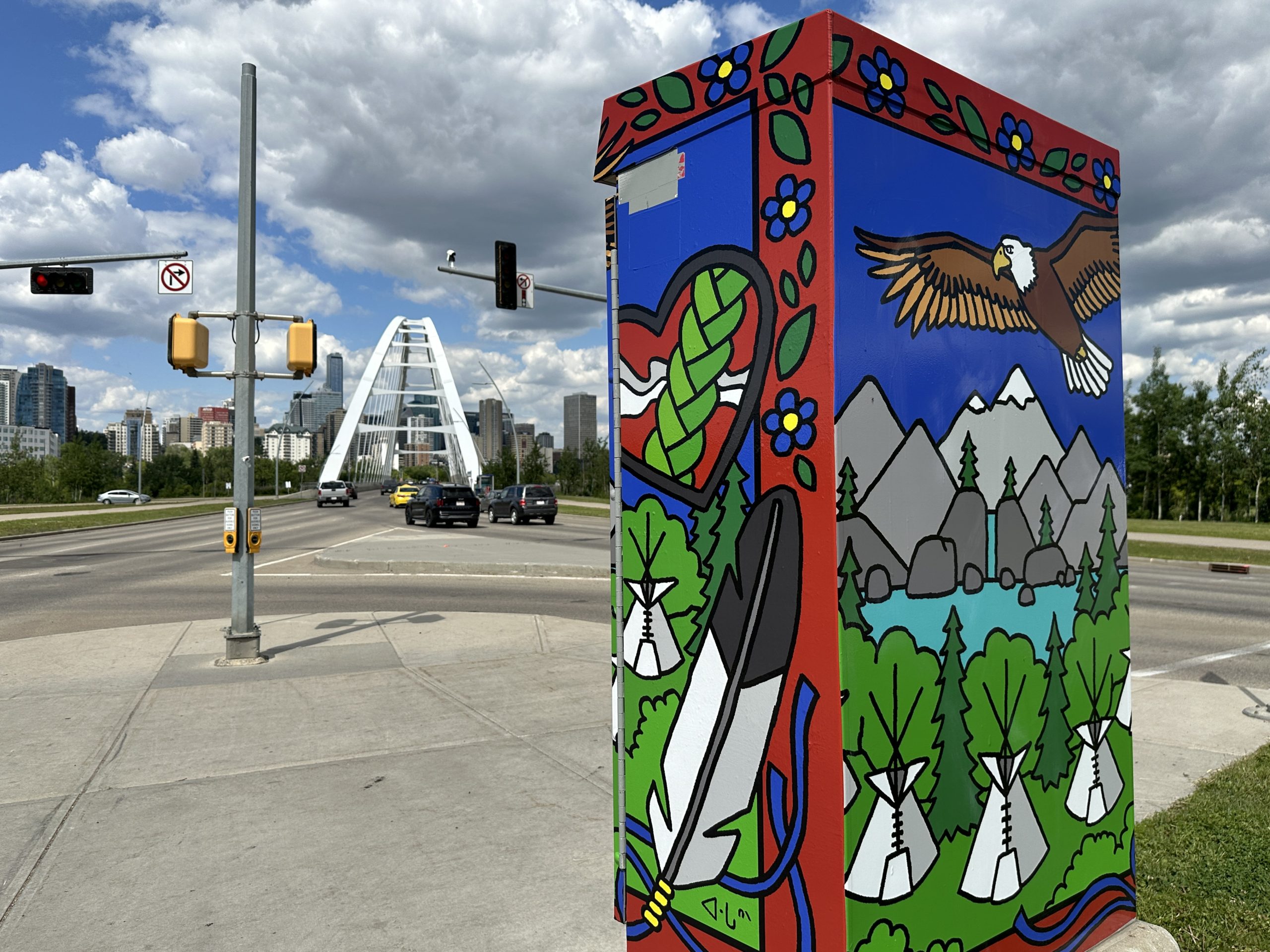 A traffic control box, wrapped with art of an eagle soaring over some mountains and tipis, stands near the entrance to the Walterdale Bridge.