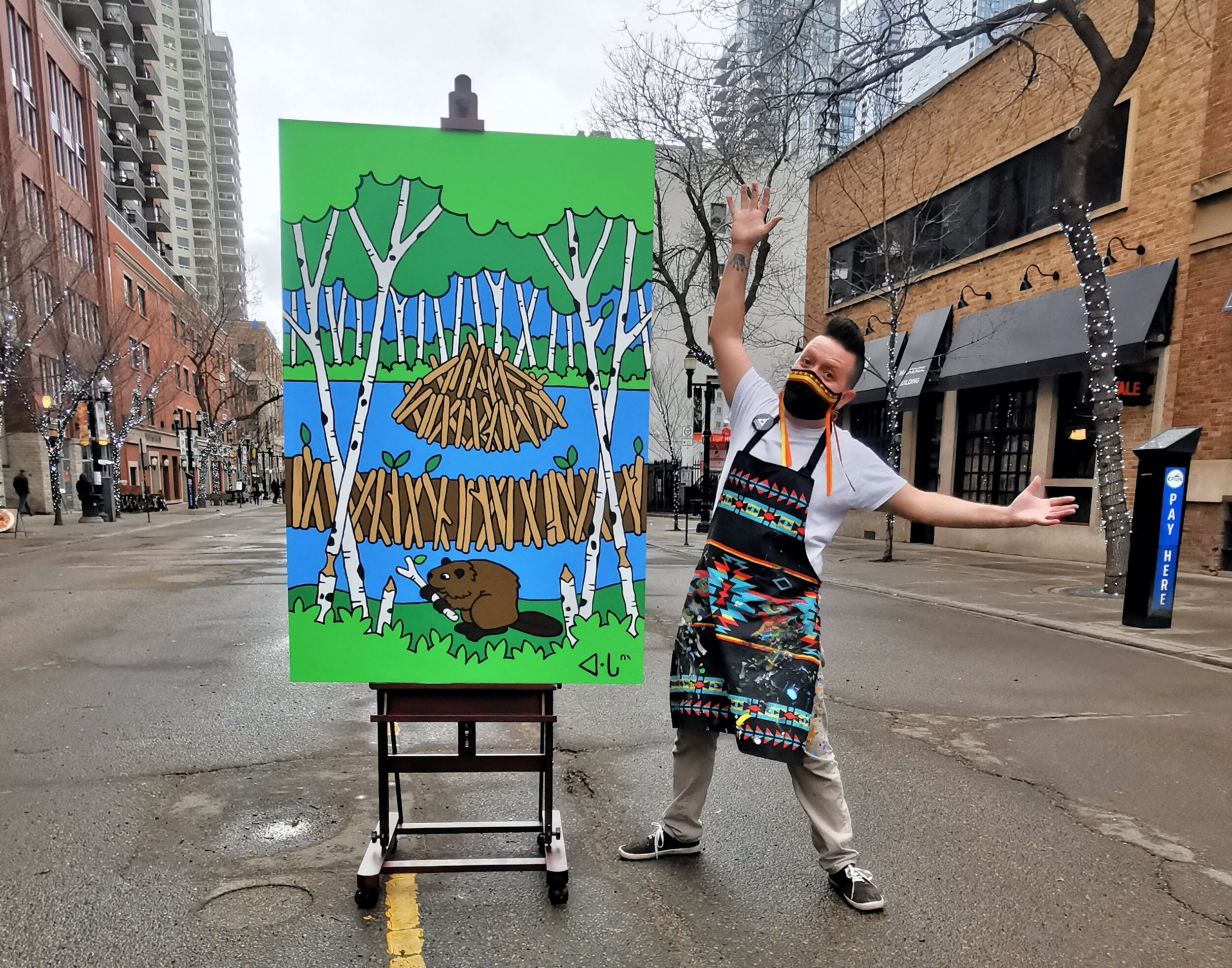 Lance Cardinal stands next to a canvas of a beaver painting sitting on an easel in the middle of 104 Street.