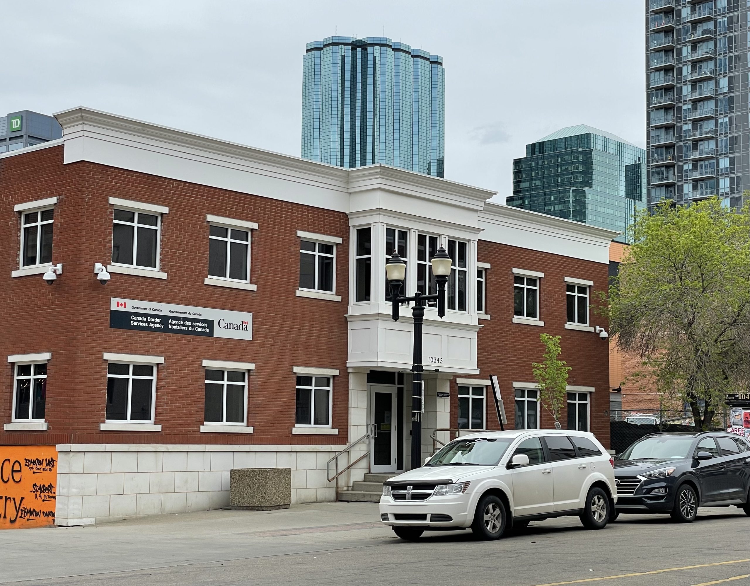 Two cars are parked in front of a brick office building.