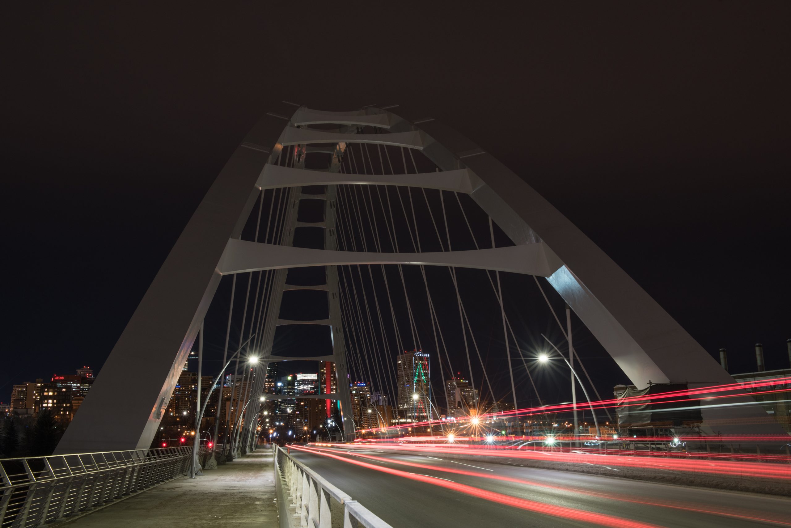 Streaking red lights across Walterdale Bridge, with downtown skyline in background