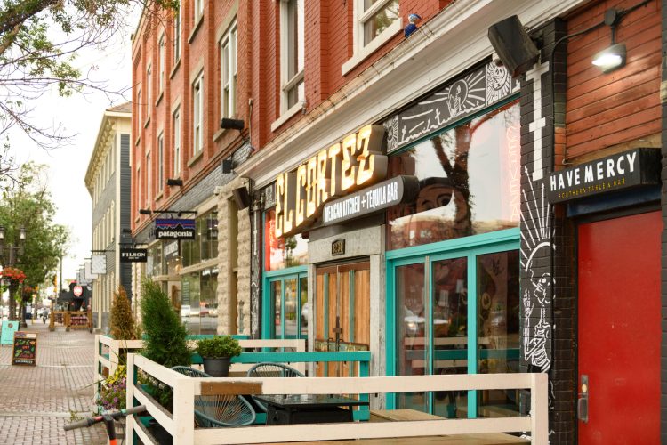 Exterior of restaurant with brightly coloured lights and trim on a paved street