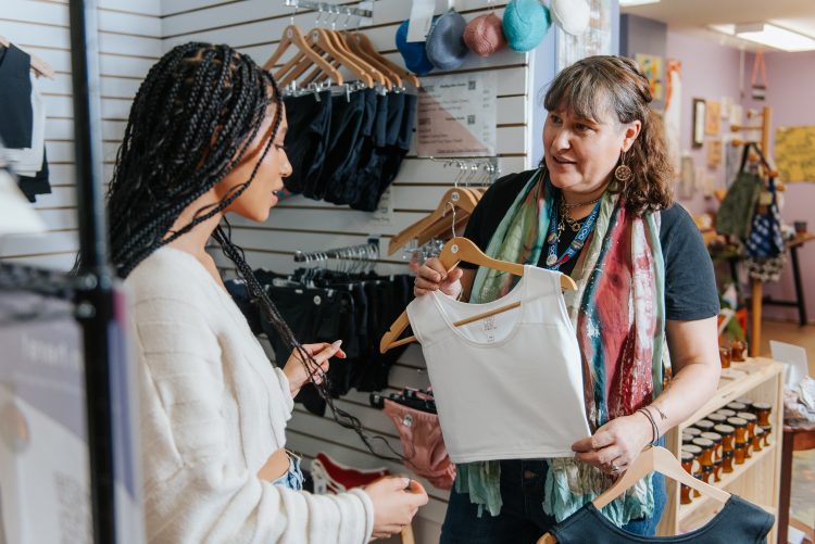 A woman interact with an employee at a clothing shop