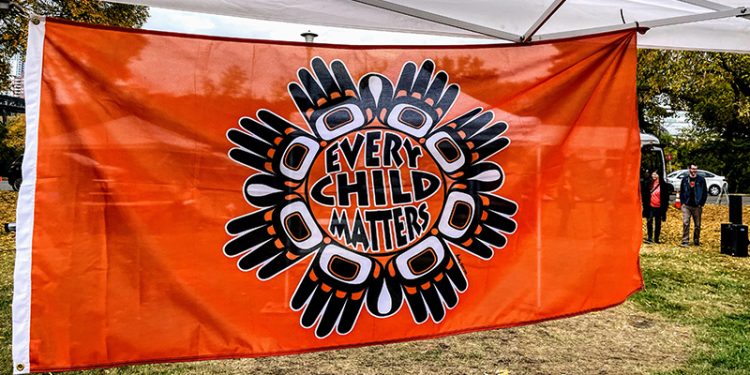 Orang flag with the words Every Child Matters surrounded by Indigenous artwork of hands