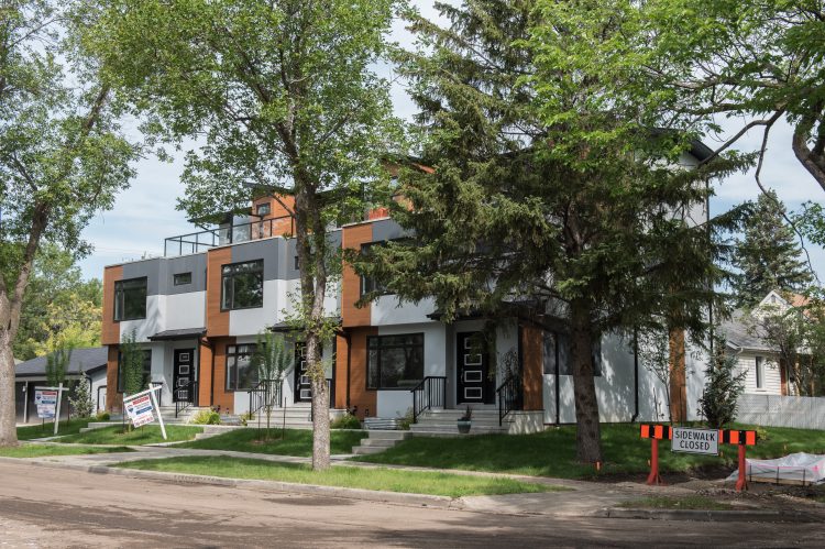 Modern row housing in surrounded by mature trees.