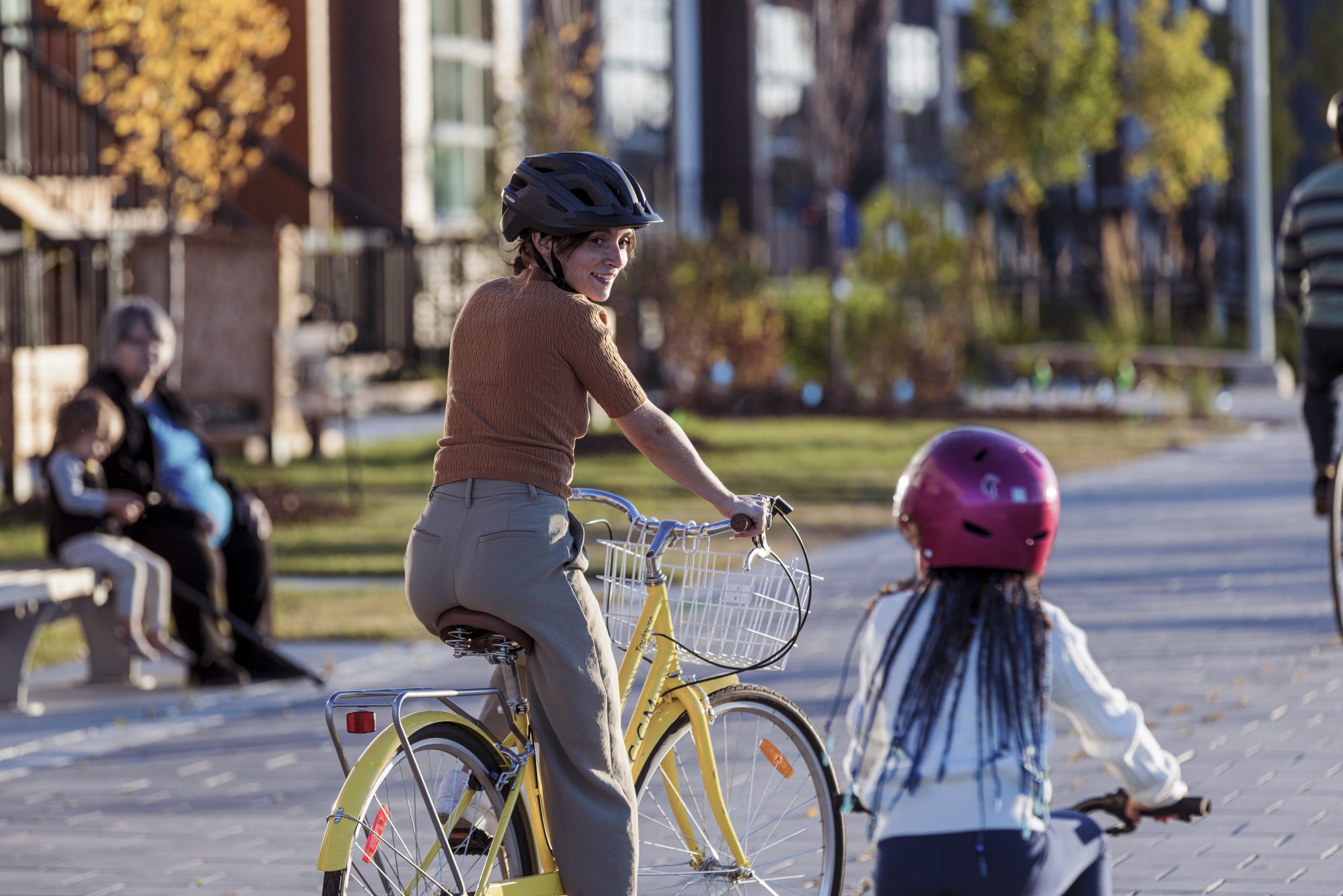 A woman and child riding bikes on a car-free street in front of houses.