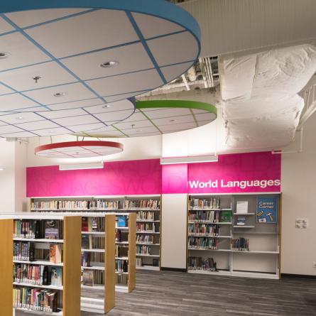 Section of a library with a pink World Languages wayfinding sign