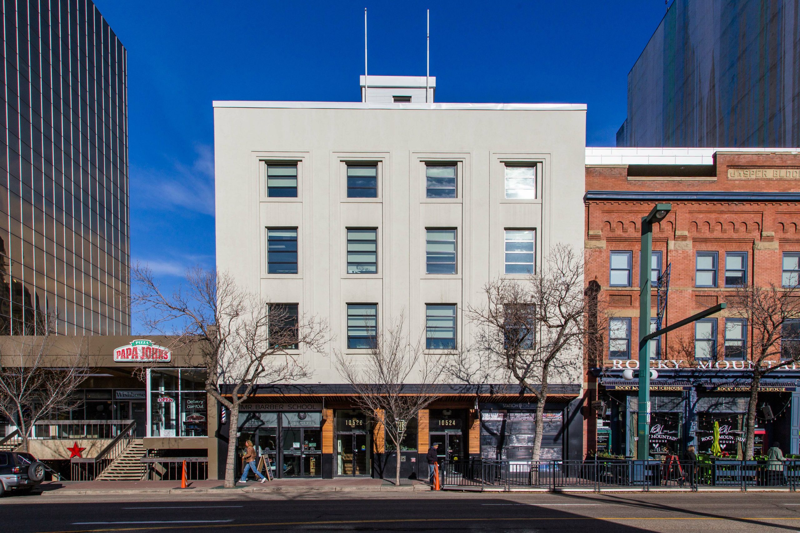 The exterior of a refurbished 4-story building with retail in the main floor and offices with windows on the top 3 floors.