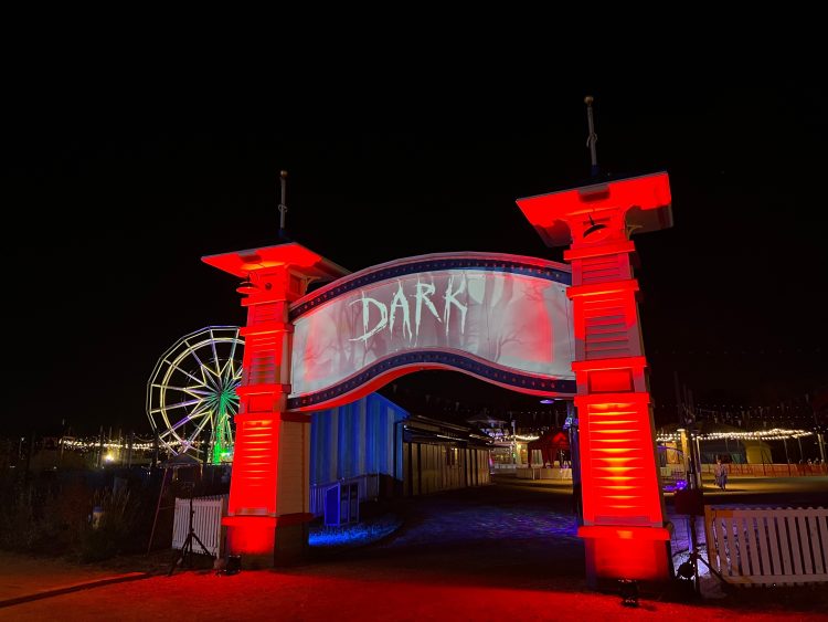 A entrance walkway with pillars lit in orange and “DARK’ in creepy letters across the top.