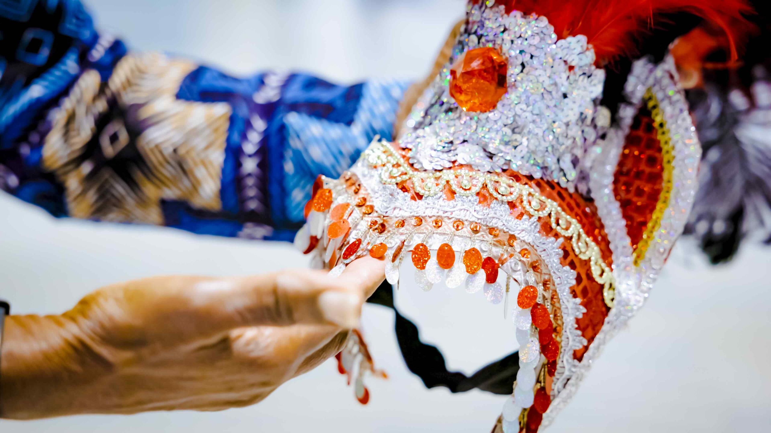 Hands hold a beaded Caribbean headdress.