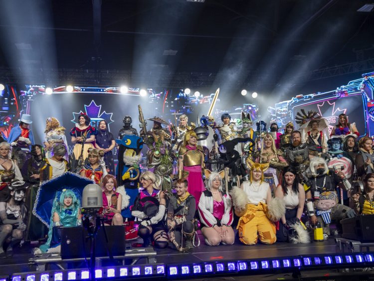 A large group of fans dressed in game costumes posing together on stage. Credit Game Con Canada