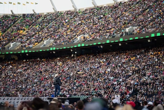 Thousands of fans in a stadium cheer on Garth Brooks.