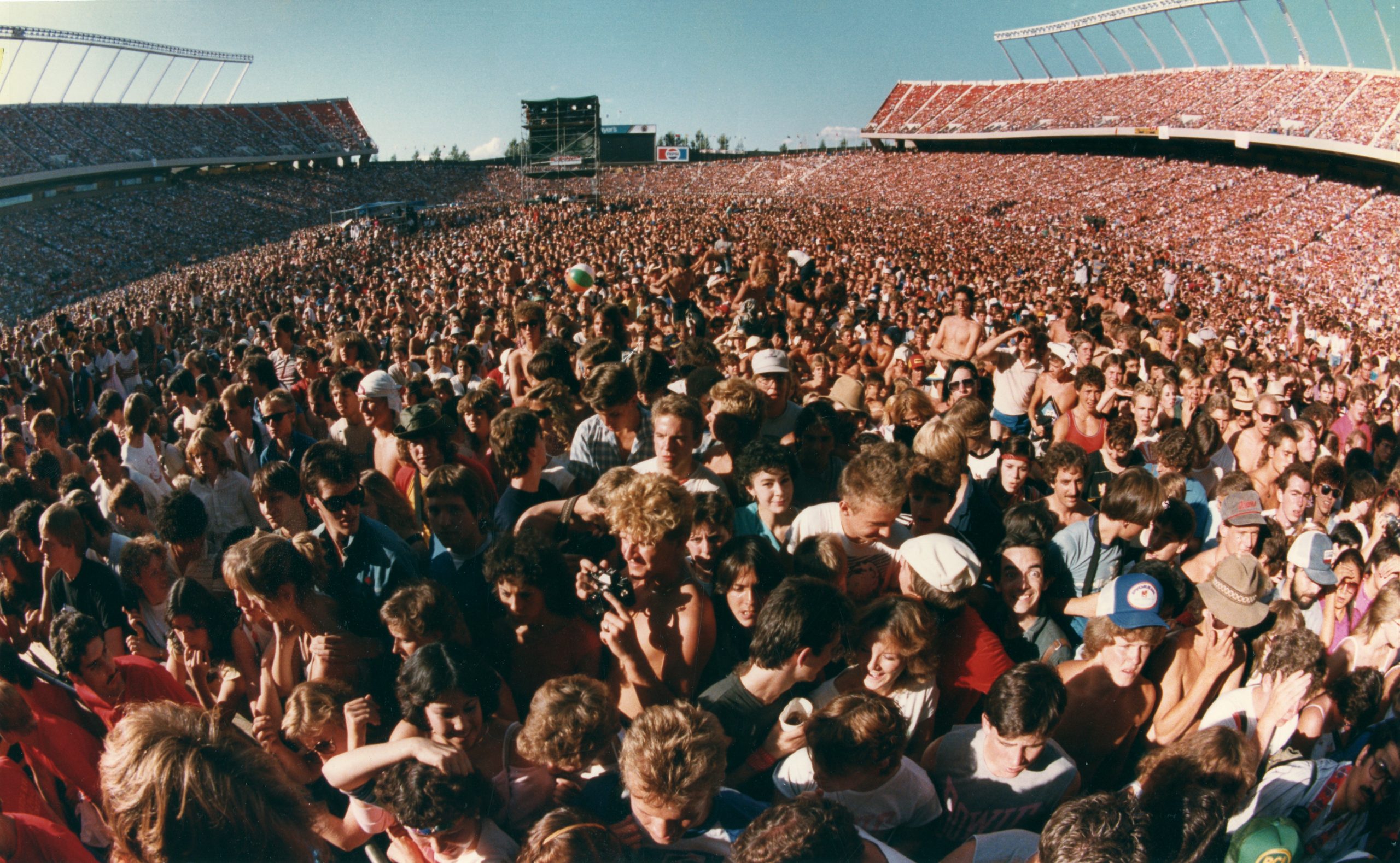 Thousands of fans standing and sitting in a stadium.