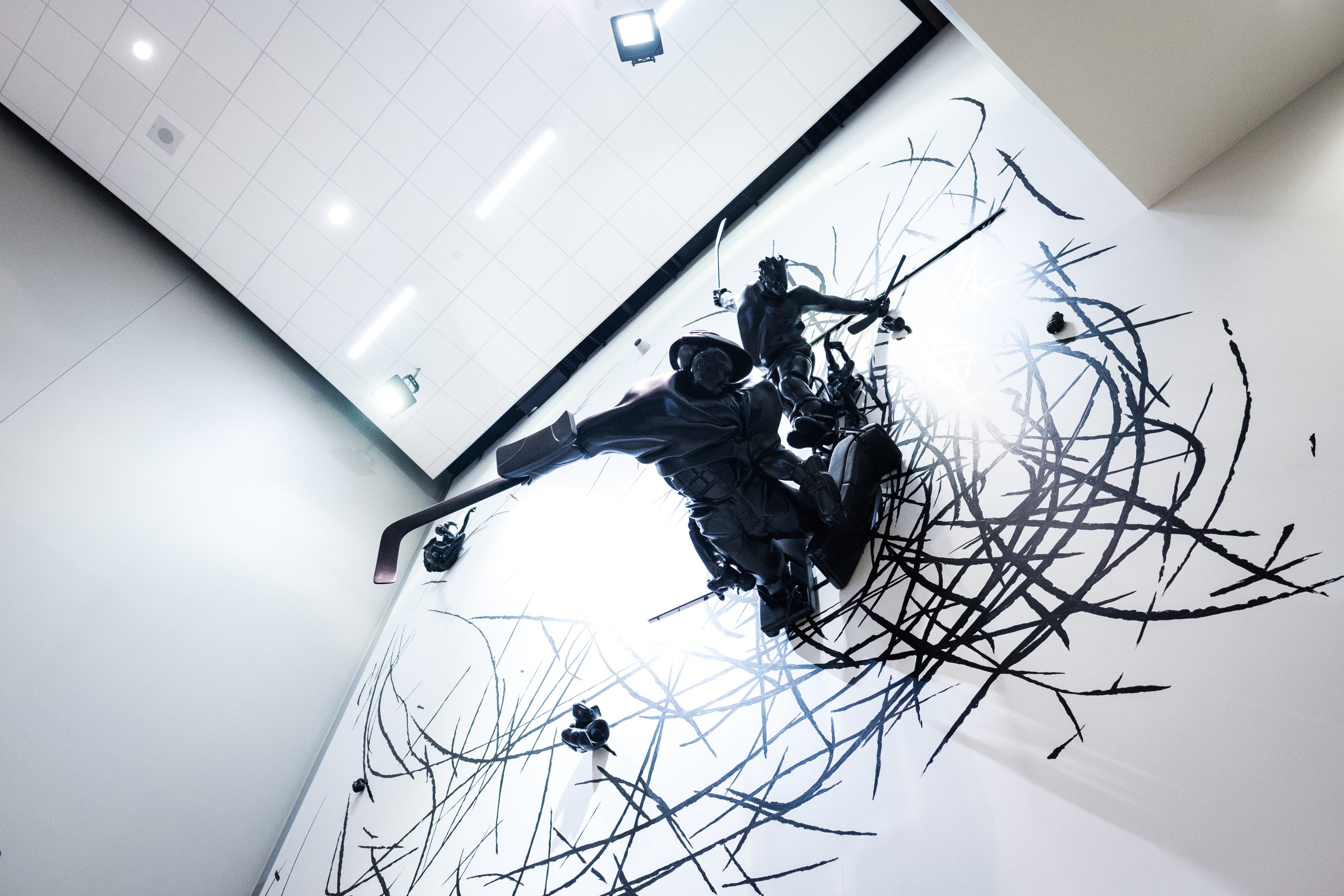 A sculpture depicting nine figures in various hockey-playing poses on a wall.