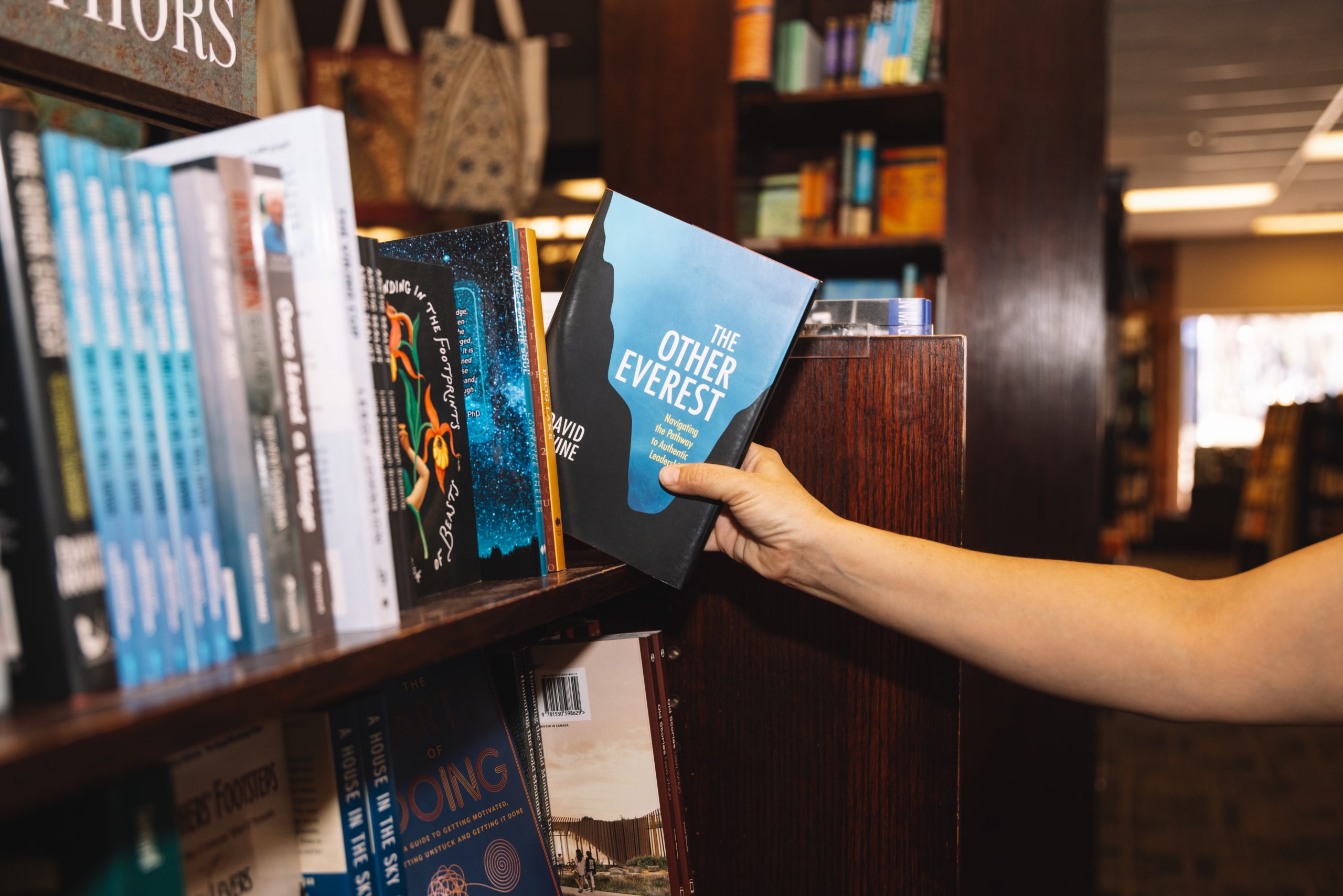 A hand removes a book from a shelf of books.