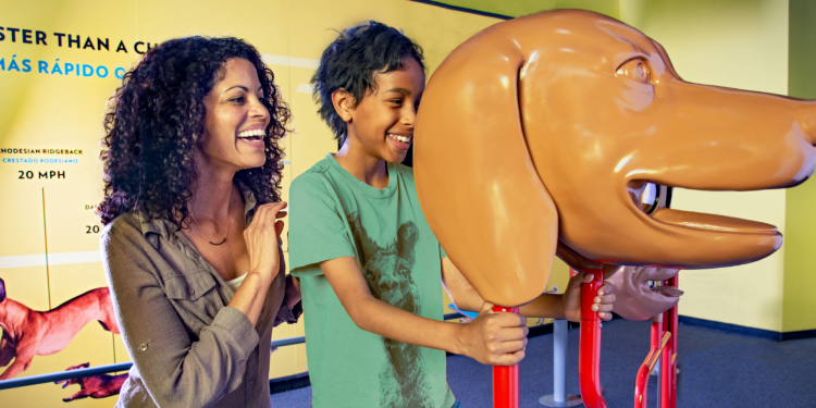 A mom and young son play with a giant figure of a dog’s head. CR-TWOS