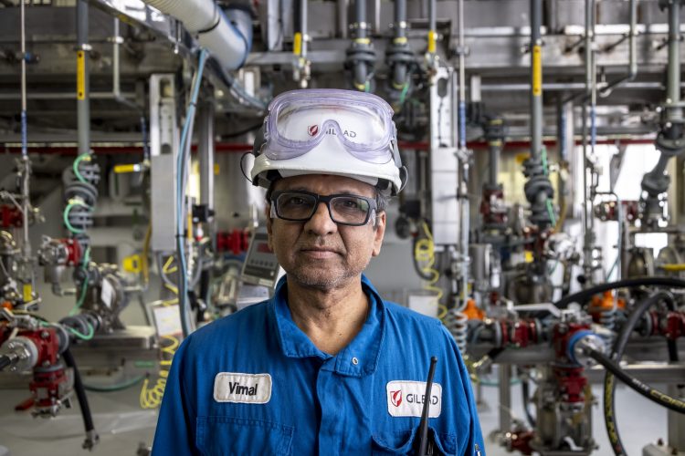 A Gilead Alberta staff member wearing Personal Protective Equipment with complex machinery in the background