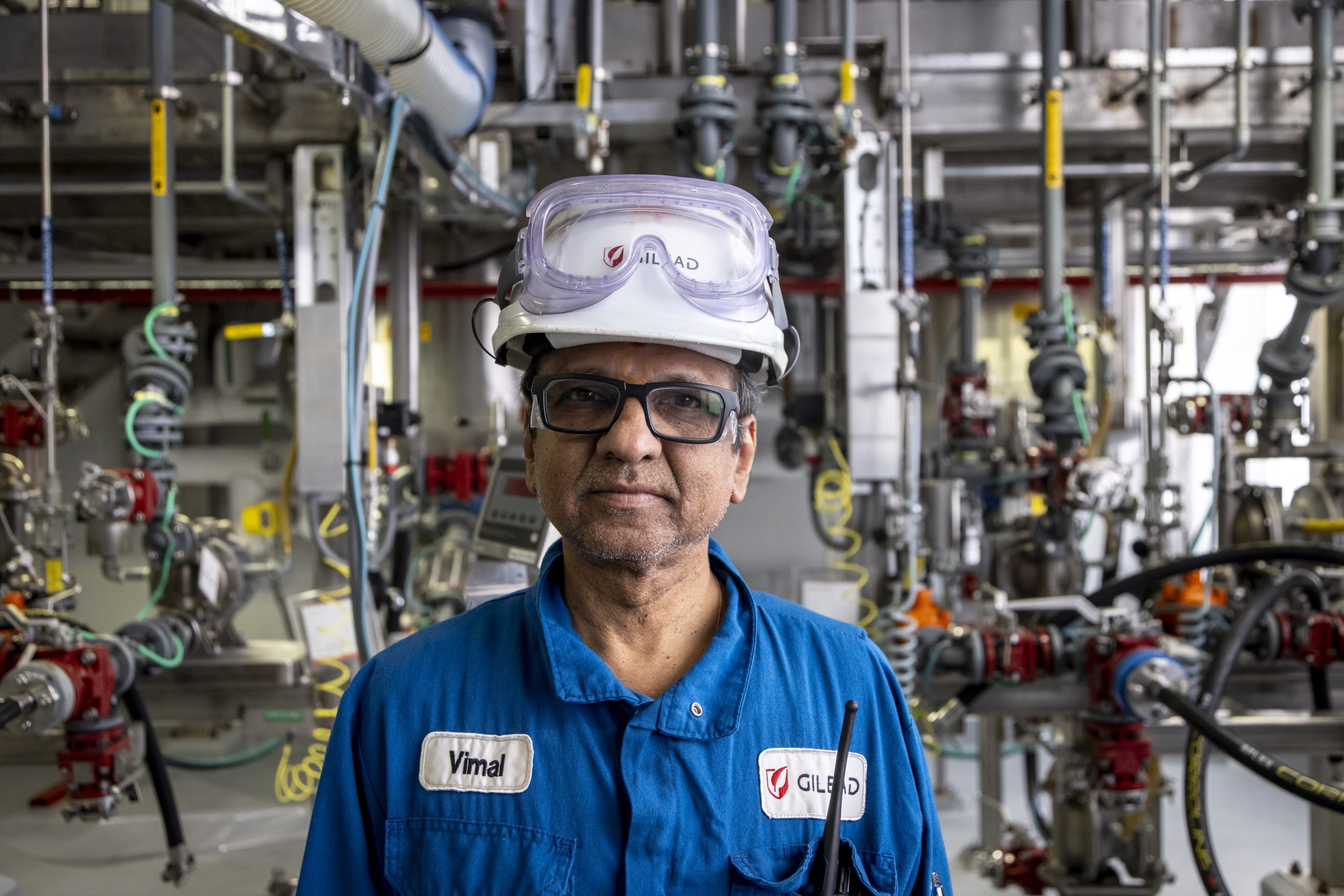 A Gilead Alberta staff member wearing Personal Protective Equipment with complex machinery in the background